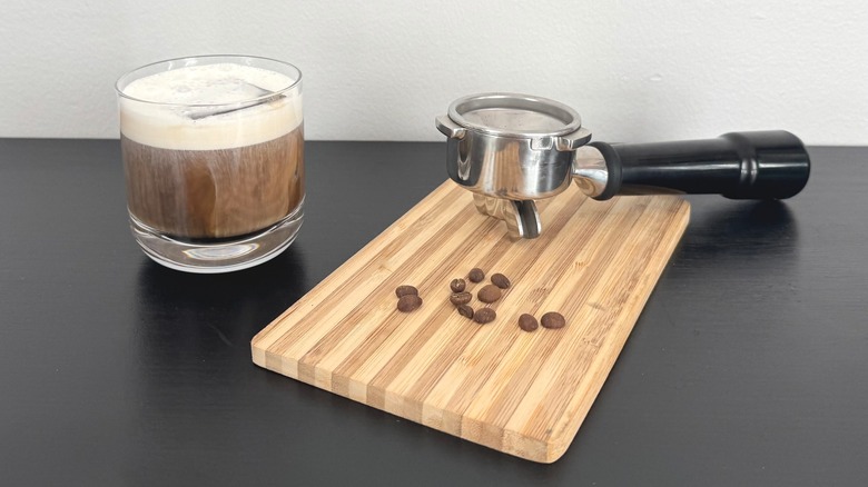 Coffee drink near cutting board with coffee beans