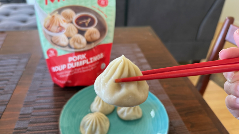 Chopsticks and spoon picking up a soup dumplings