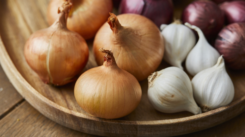 assorted onions and garlic in a wooden bowl