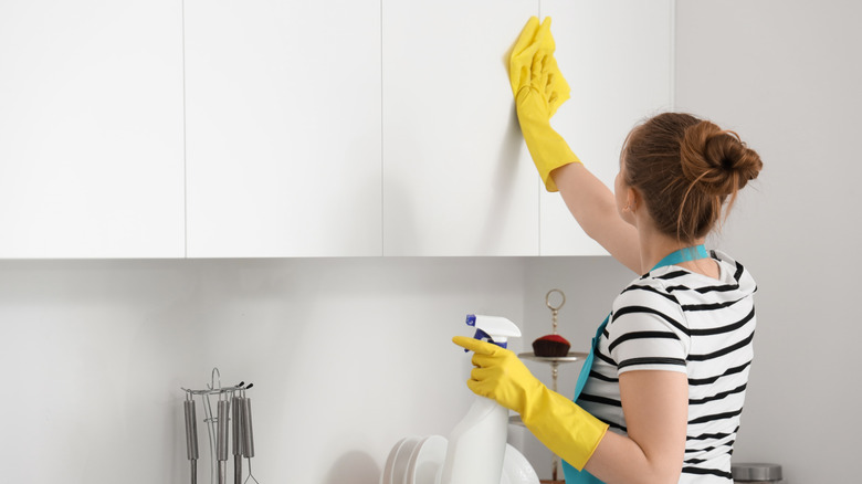 Woman cleaning kitchen cabinet doors