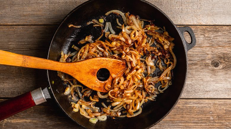 Caramelized onions in a pan with a wooden spoon