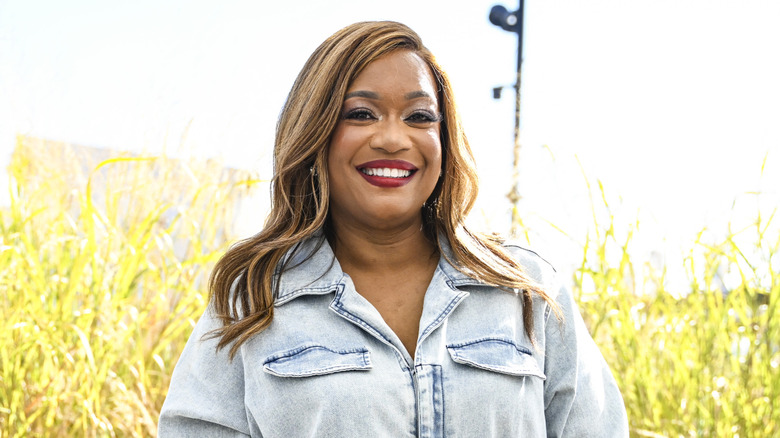 sunny anderson posing in a jean jumpsuit