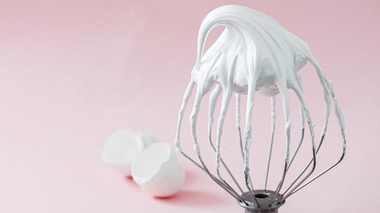 whipped meringue on a beater with eggshells in background
