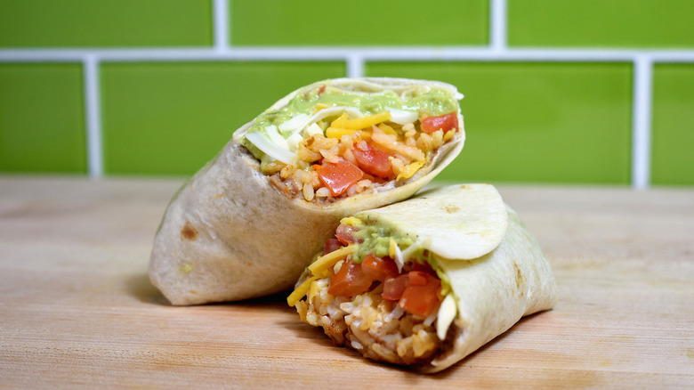 A Taco Bell 7-Layer burrito cut in half on a board