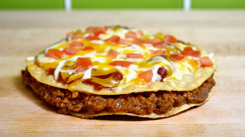 Mexican pizza on counter in front of green tiles