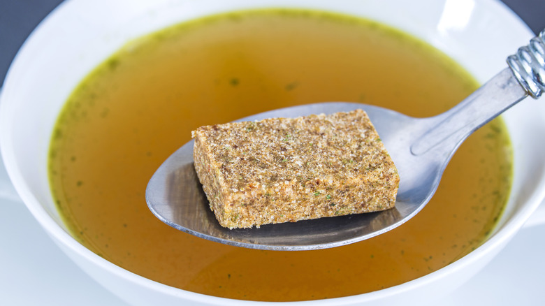 Bouillon cube in spoon over soup