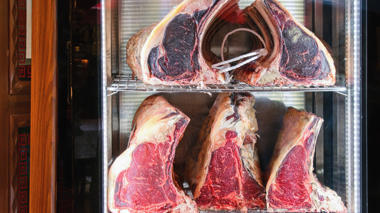 Raw, dry-aged ribeye steaks in a clear glass cabinet