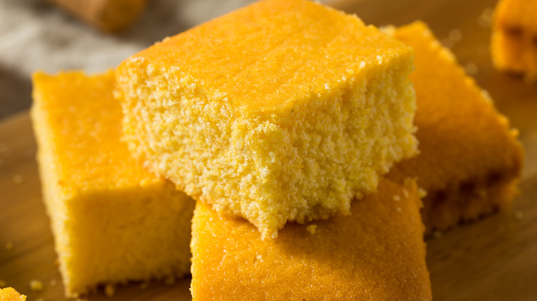 Squares of cornbread piled on wooden table