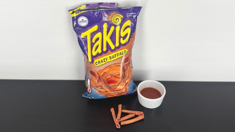A bag of Crazy Buffalo Takis with a bowl of buffalo sauce