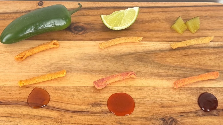 A cutting board with various Takis and food items