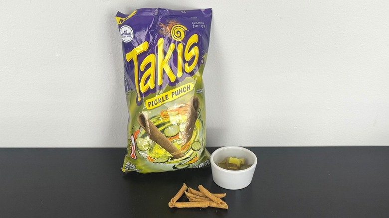 A bag of Pickle Punch Takis with a bowl of pickles