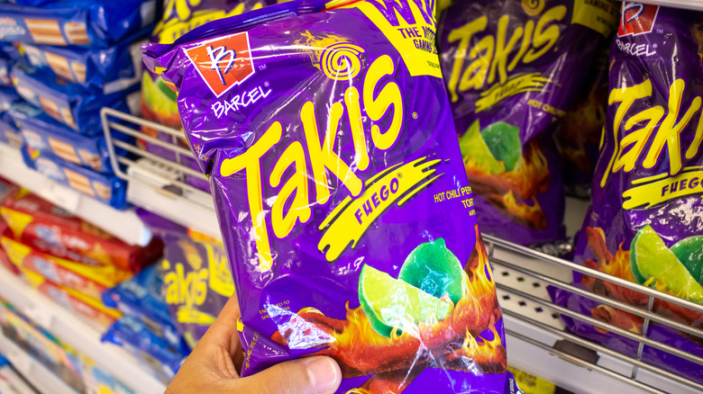A person holds a bag of Fuego Takis