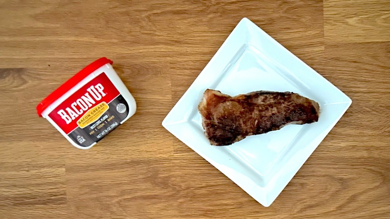 Tub of Bacon Up and seared steak on a square white plate