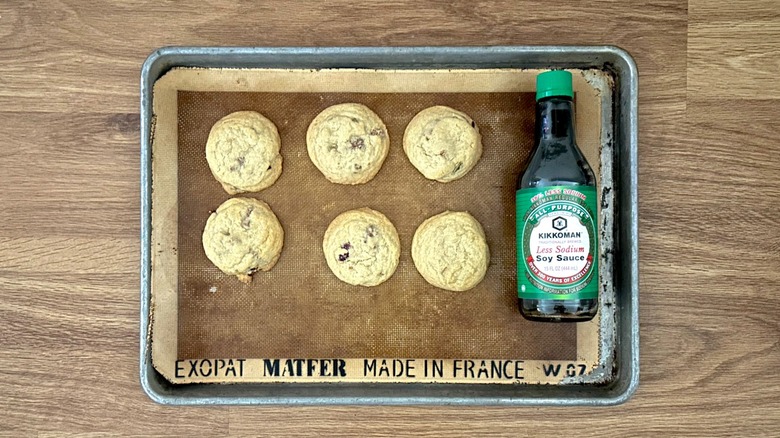 Half a dozen freshly baked cookies on a cookie sheet and bottle of Kikkoman soy sauce
