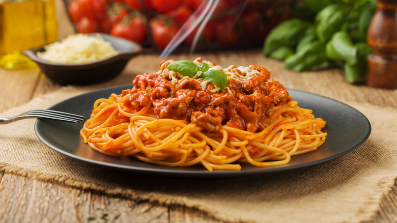 A plate of spaghetti bolognese with produce in background