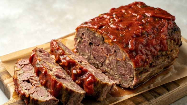 Sliced meatloaf sitting on a wooden serving board