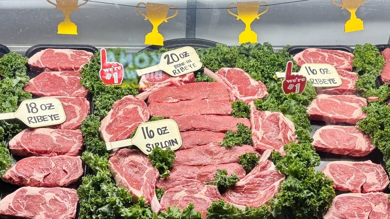 Refrigerated case of steaks on bed of lettuce with labels