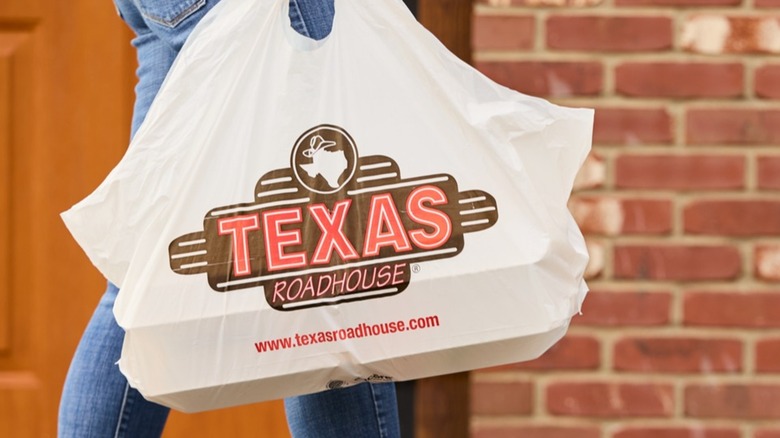 Person carrying takeout bag from Texas Roadhouse