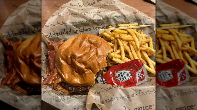 A half-eaten Jaggers burger, with fries and a tomato ketchup packet