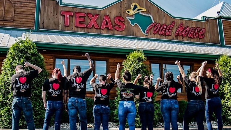 Texas Roadhouse employees in front of the restaurant with arms up