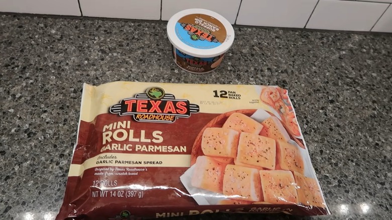 A bag of Texas Roadhouse garlic parmesan mini rolls next to a tub of the buffalo ranch dip