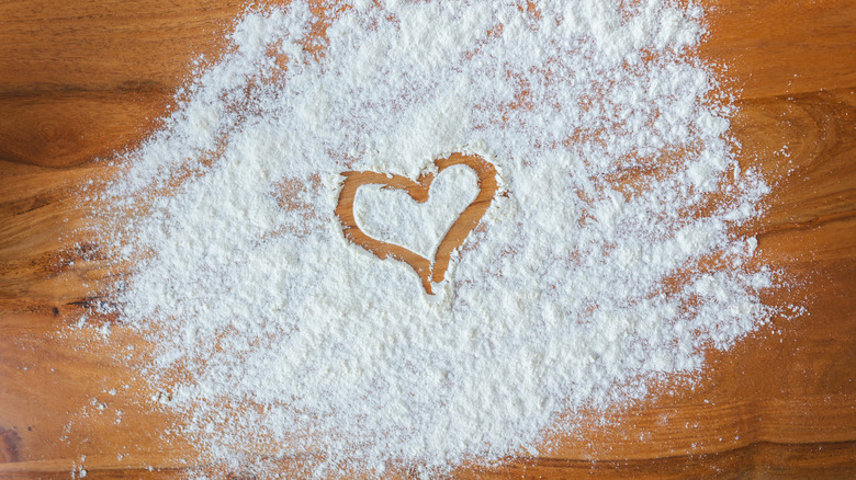 A heart is drawn in flour on a wooden surface