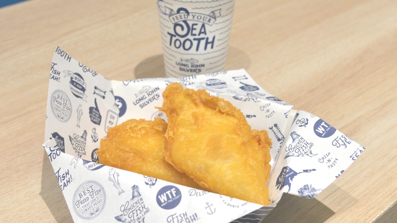a basket of two pieces of fried fish from Long John Silver's on a table with a drink