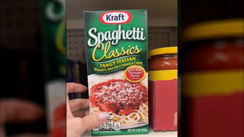 A hand holding a box of Kraft Spaghetti Classics Tangy Italian Meal Mix