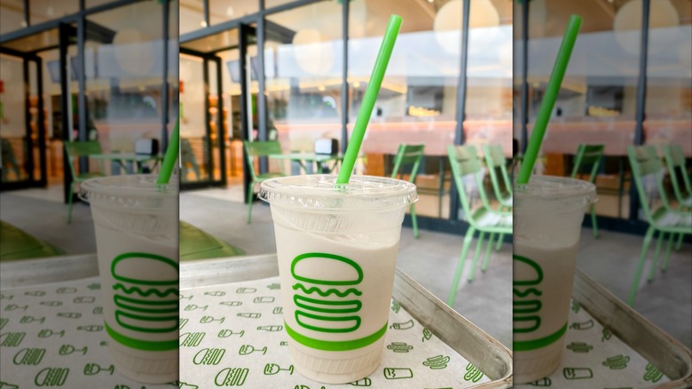 Shack Shack shake on table in a plastic cup with a green straw