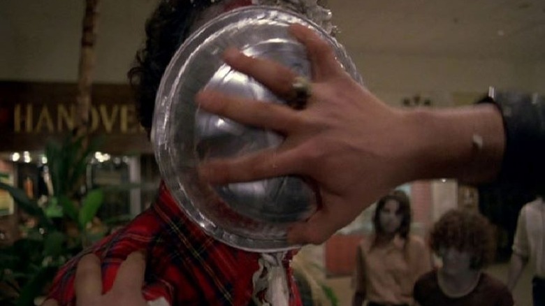 A hand pushes a pie tin into the face of a zombie, seen in a still from "Dawn Of The Dead"