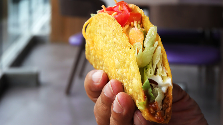 Hand holding Taco Bell crunchy taco