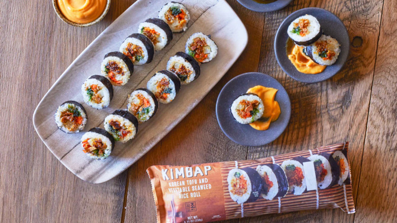 A Trader Joe's kimbap roll served on a wood plate next to its packaging