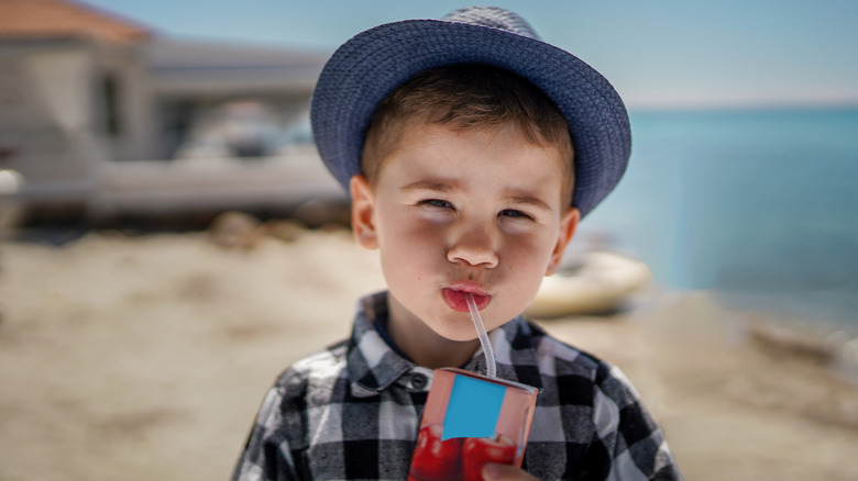boy drinking juice on beach