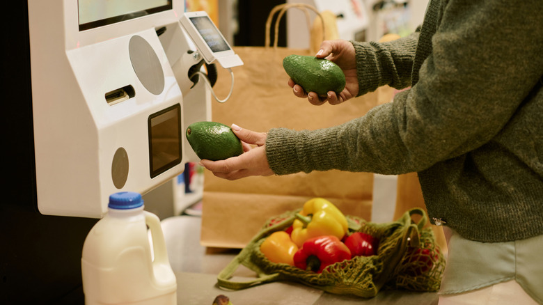 A customer scans many groceries at a self-checkout machine.