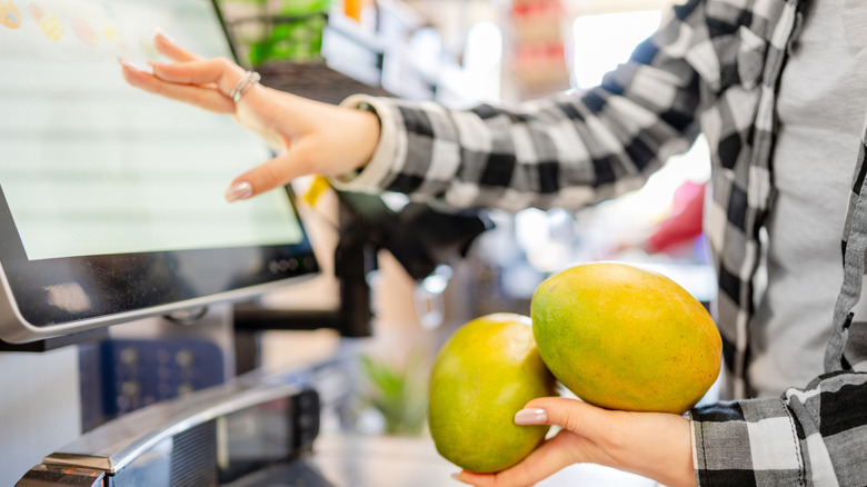 A person scans mangoes at a self-checkout machine.