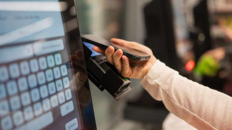 A person scans their phone on a self-checkout machine.