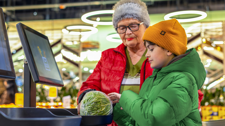 A child scans a head of lettuce at a self-checkout.