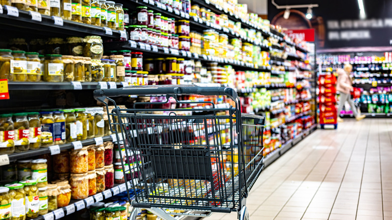 A shopping cart is in a supermarket aisle.