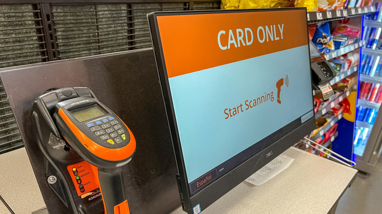 A self-checkout machine in a grocery store displays a card-only sign.