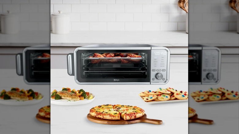 A Ninja Flip Toaster Oven/Air Fryer placed with fish, vegetables, pizza, cookies, and chicken wings