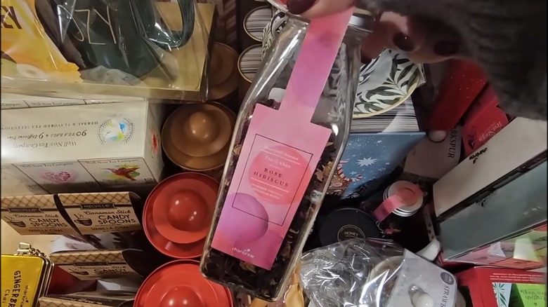 a hand holding a bottle of loose leaf tea with a pink label