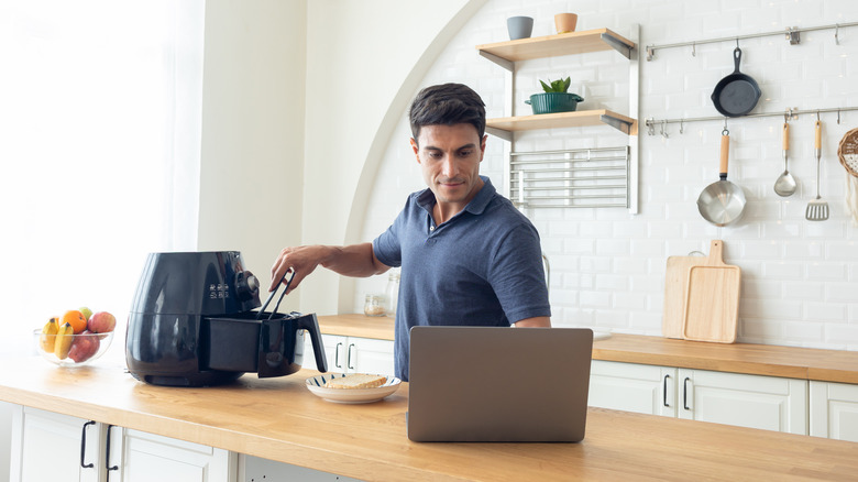 Man reading air fryer manual online