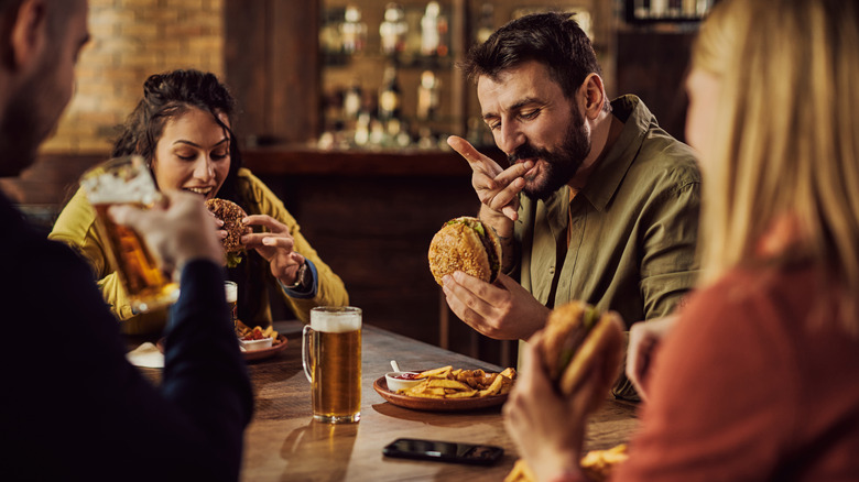 people drinking and eating burgers