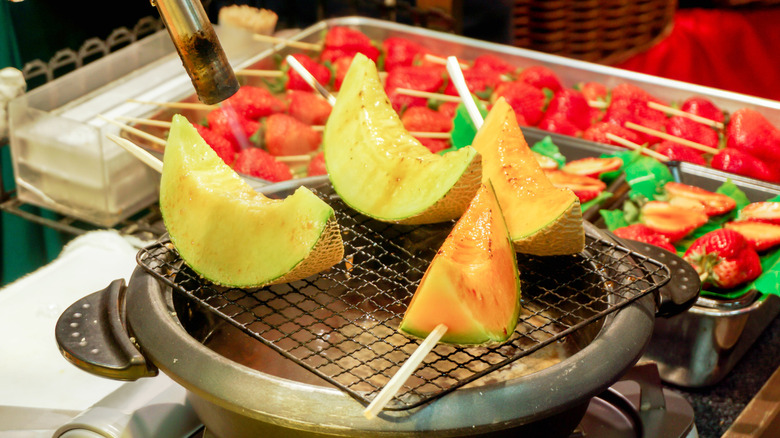 Slices of cantaloupe skewered and cooking on a grill