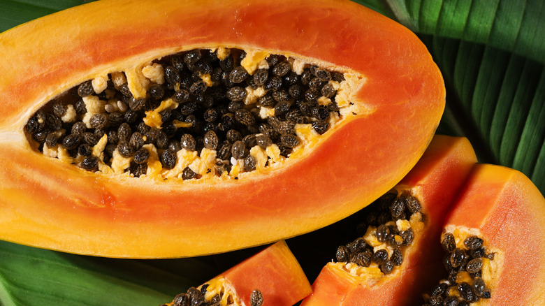 A closeup shot of a papaya sliced in half with seeds