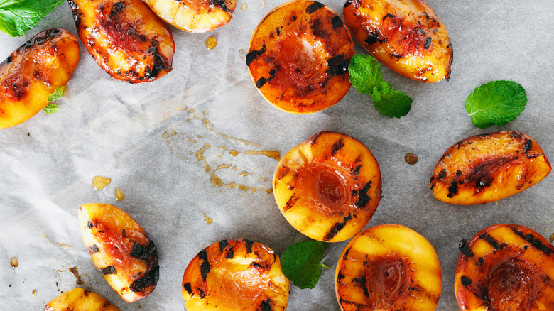 Grilled peaches arranged on a countertop with mint for garnish