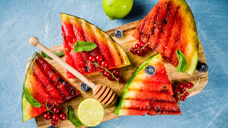 Grilled watermelon triangles on a wooden board garnished with mint and cranberries