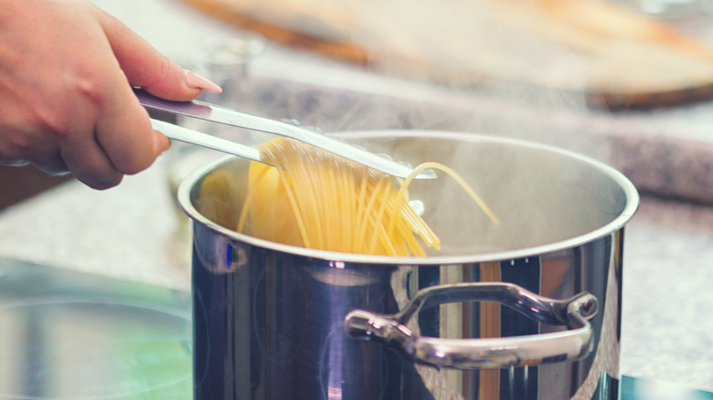 Person cooking spaghetti noodles