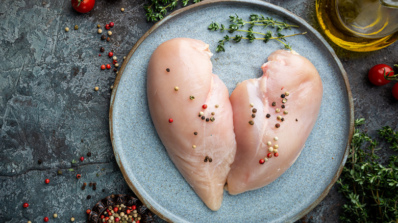 Raw chicken breasts on plate