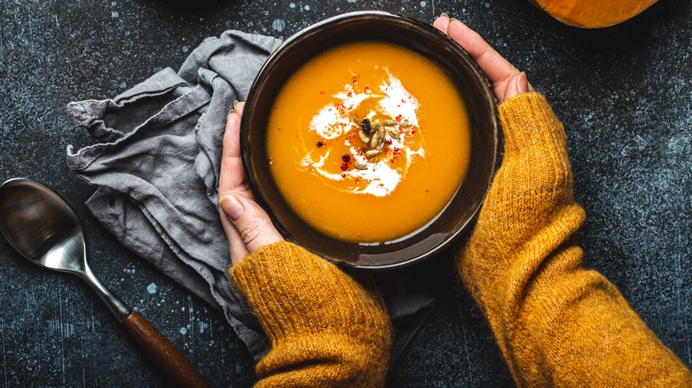 Hands holding bowl of soup